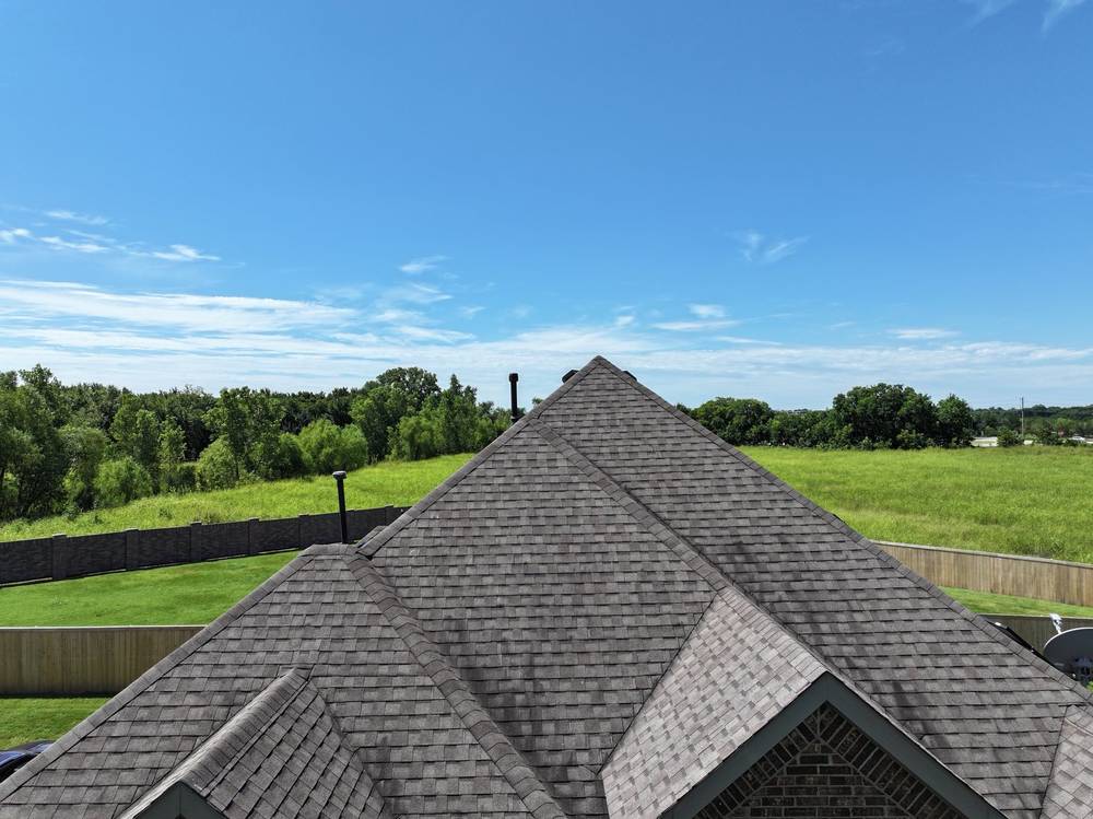 Finished gray architectural shingle roof, ridge line against a blue sky