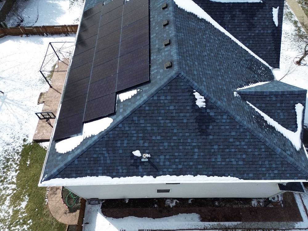 Close aerial of architectural shingles, ridge caps and a solar array on a Bolingbrook, IL home