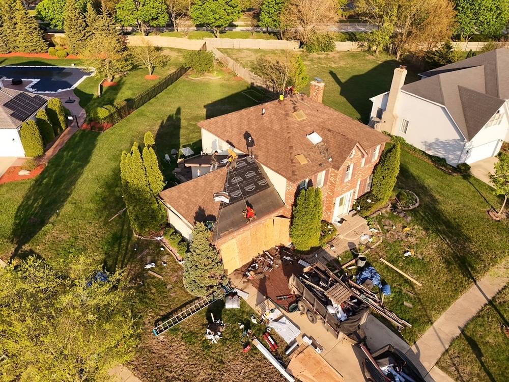 Roof replacement in progress on a brick home in Oak Brook, IL, crew on the roof and materials staged