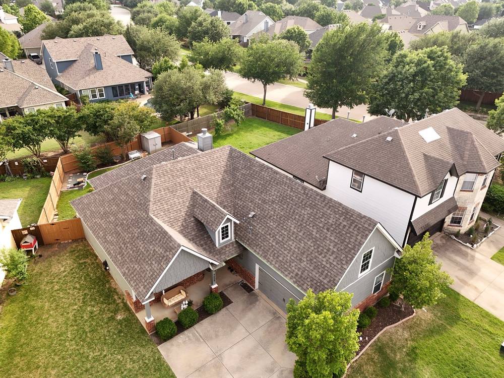New weathered-wood shingle roof on a gray two-story home, aerial