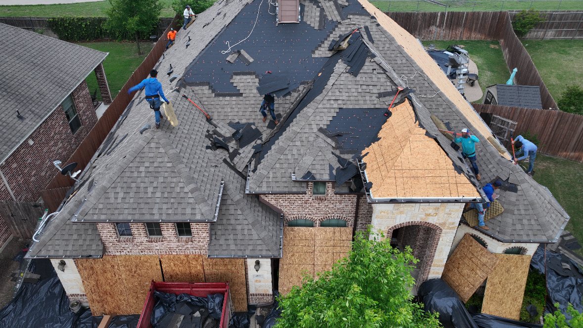 Exposed roof decking during a full tear-off with the crew working