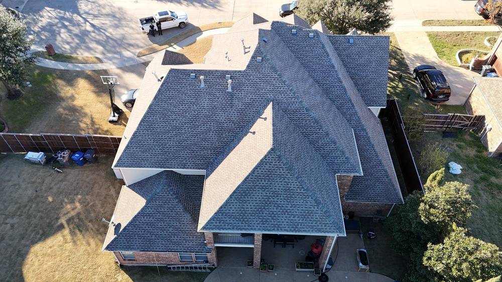 Drone inspection of a gray shingle roof on a brick two-story home, rear view