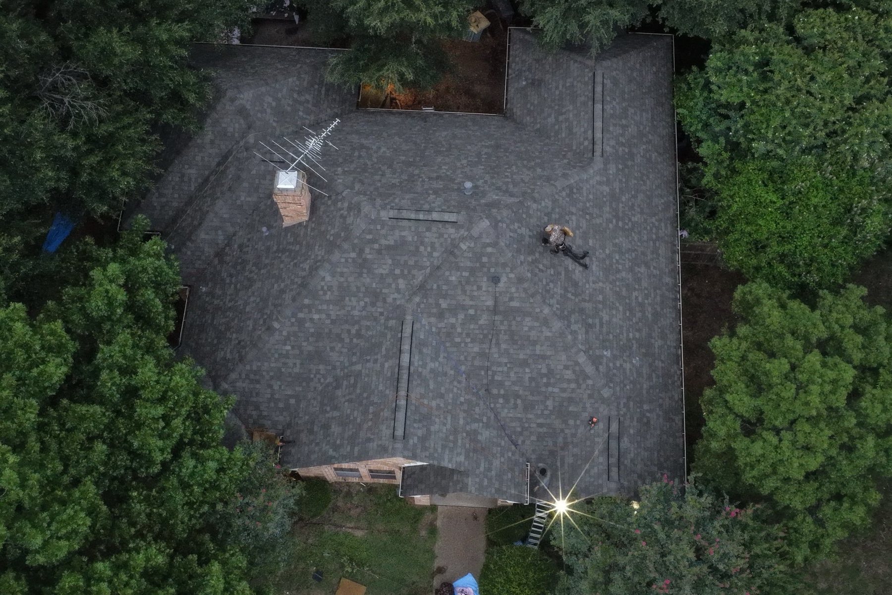 Aerial view of a roof mid-replacement, old shingles torn off with new underlayment down