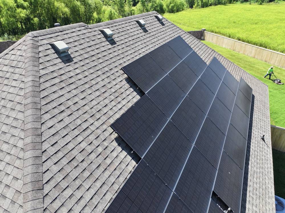 Close aerial of gray architectural shingles next to a rooftop solar array