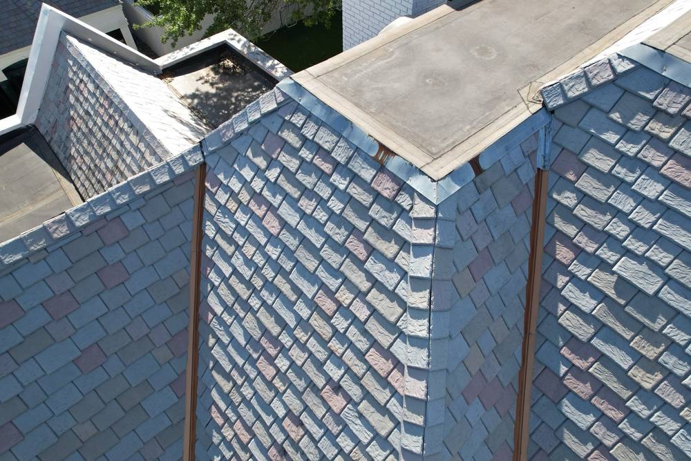 Close aerial of a premium synthetic slate roof with copper-tone valley flashing