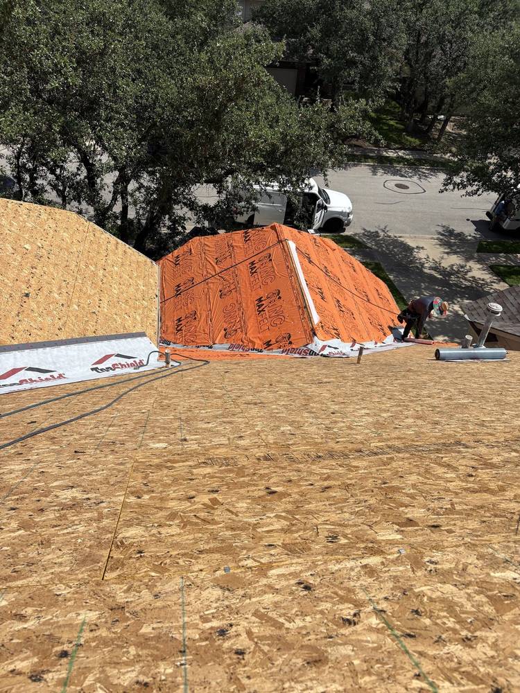New decking and orange synthetic underlayment going down during a dry-in